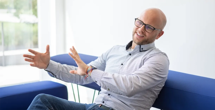 Eine Person sitzt auf einer Couch und gestikuliert mit den Händen.
